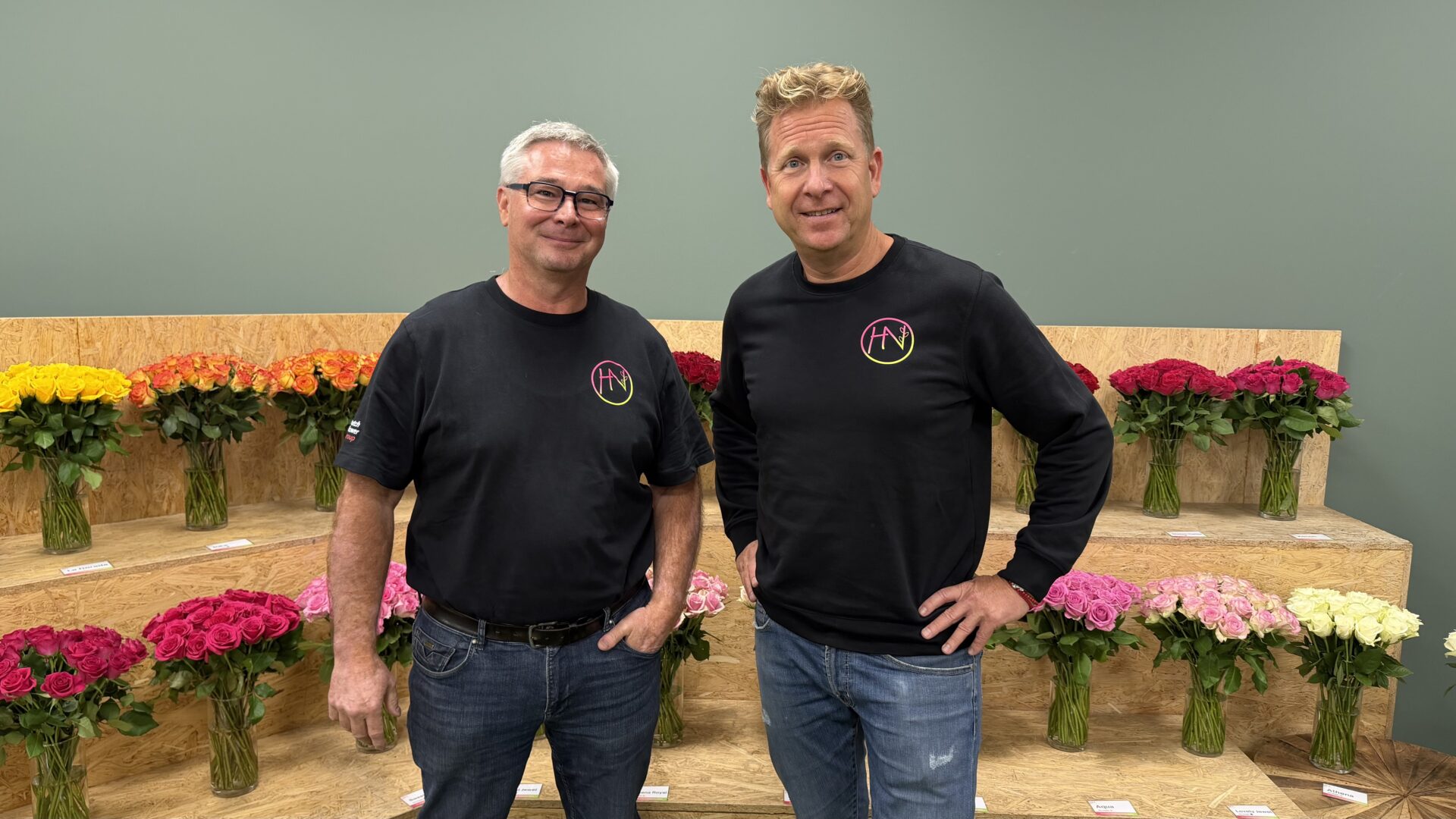 Philippe Veys en Marco van der Burg bij Herburg Roses en Nini, met verschillende soorten rozen op de achtergrond.
